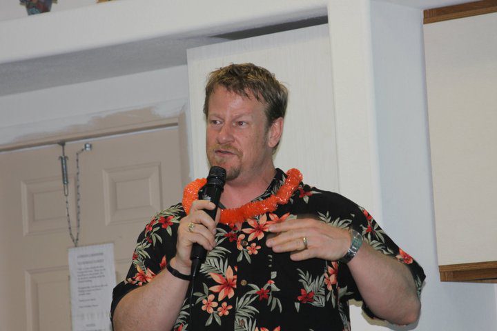 James Raymond Riddle in tropical outfit with mic